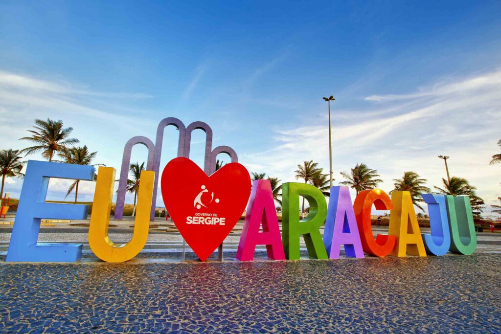 Letreiro Eu Amo Aracaju na Orla de Atalaia, com coqueiros ao fundo
